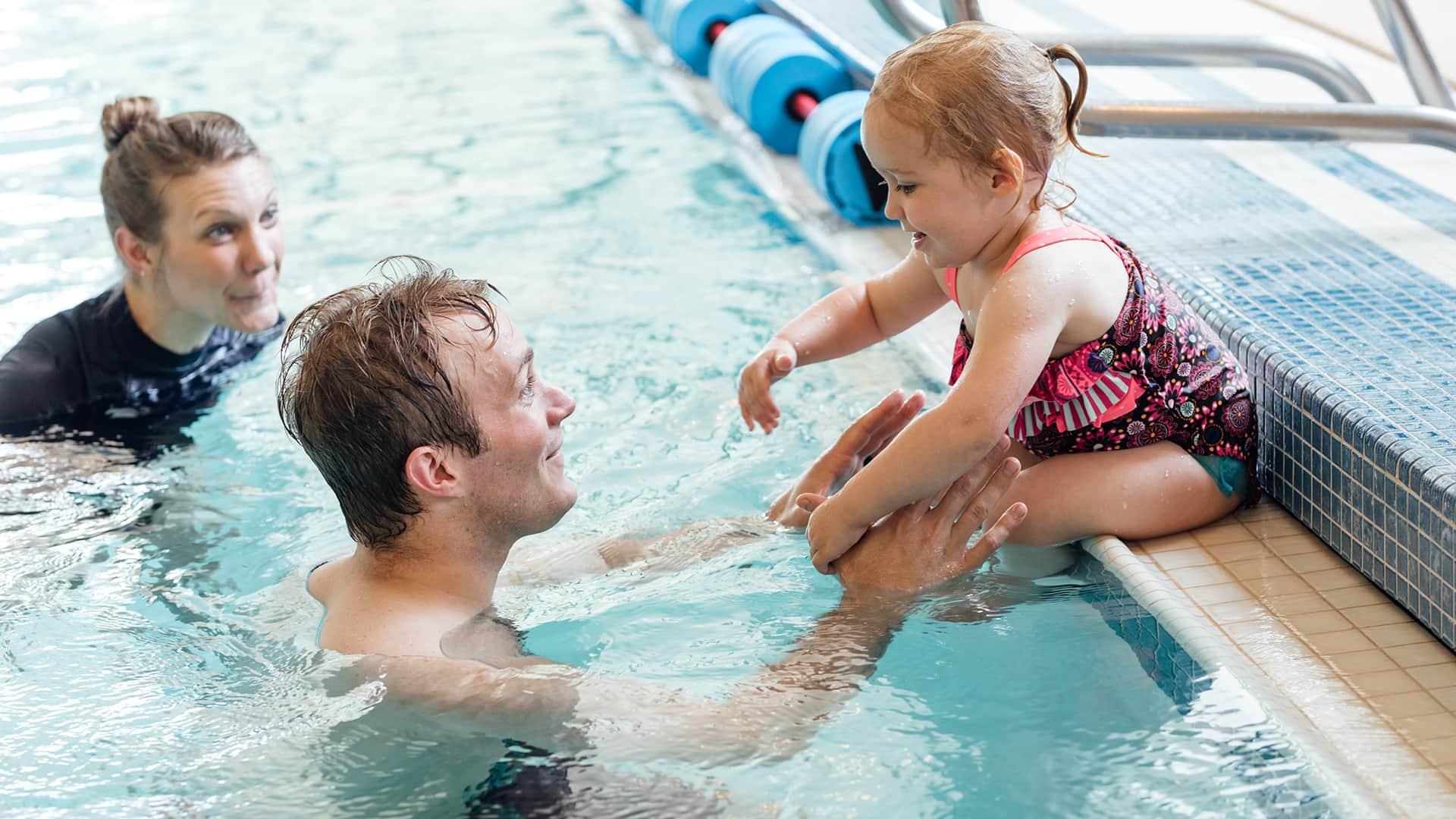 Two adults teach young child to swim at PRO Club