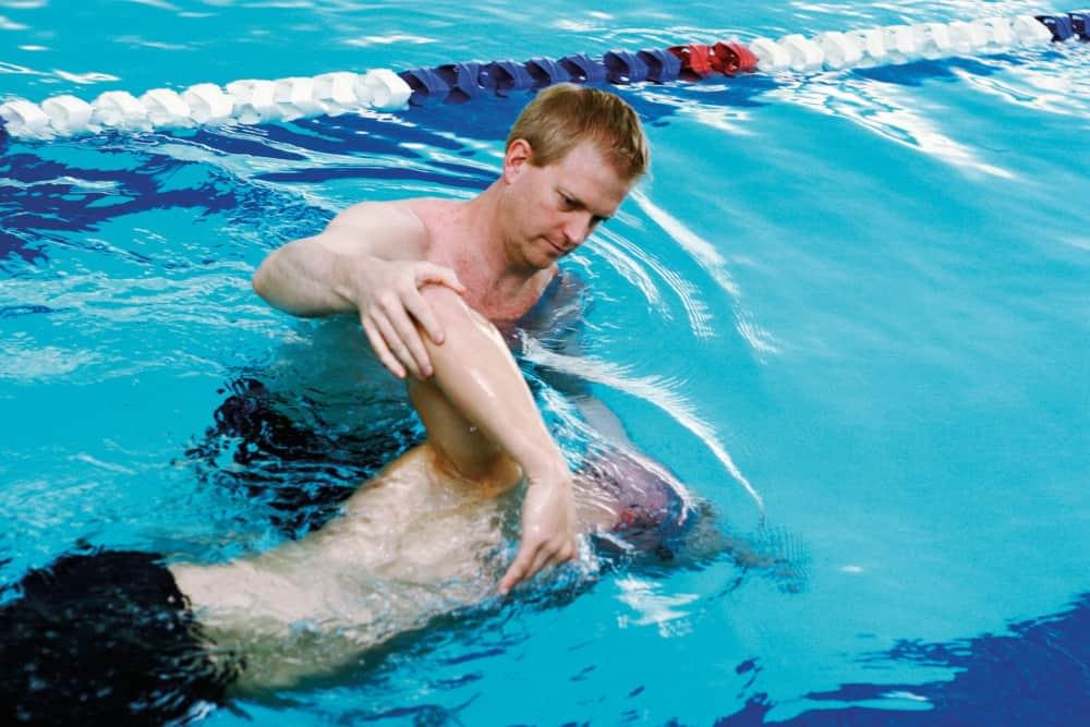 Blonde man helping person learn to swim at PRO Club Aquatics