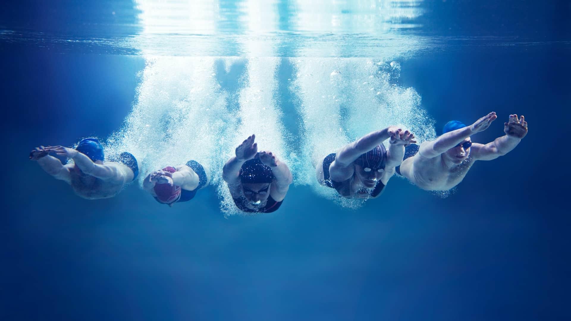 Five people wearing swim caps swimming at PRO Club