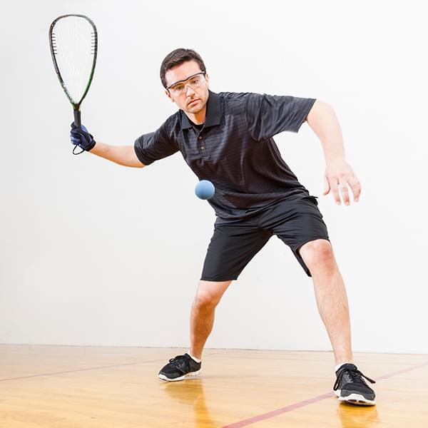 Man in black workout gear hitting a racquetball