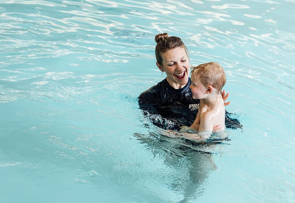 A Pro Club instructor teaching a toddler how to swim