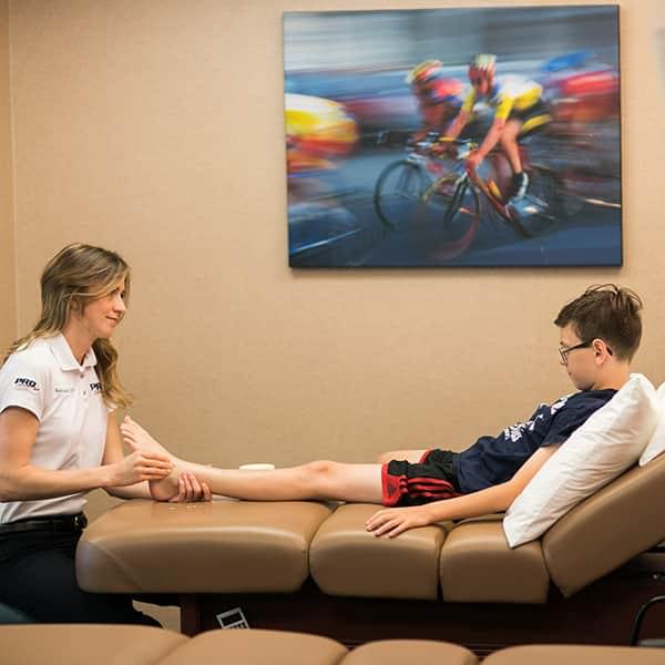 Physical therapist assisting young patient at PRO Club Physical Therapy