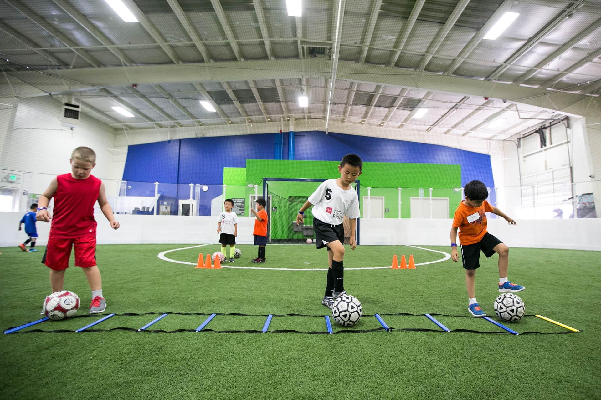 Three boys kicking soccer balls at the Indoor Soccer Arena at PRO Club